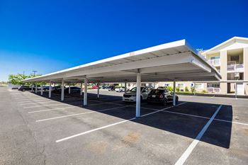 A parking lot with a white canopy and cars parked underneath.